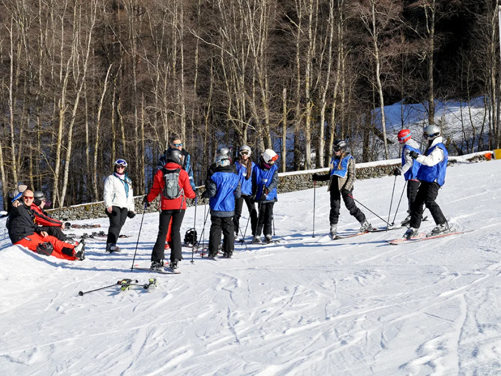 Skigruppe sammelt sich am Pistenrand vor dem Wald.